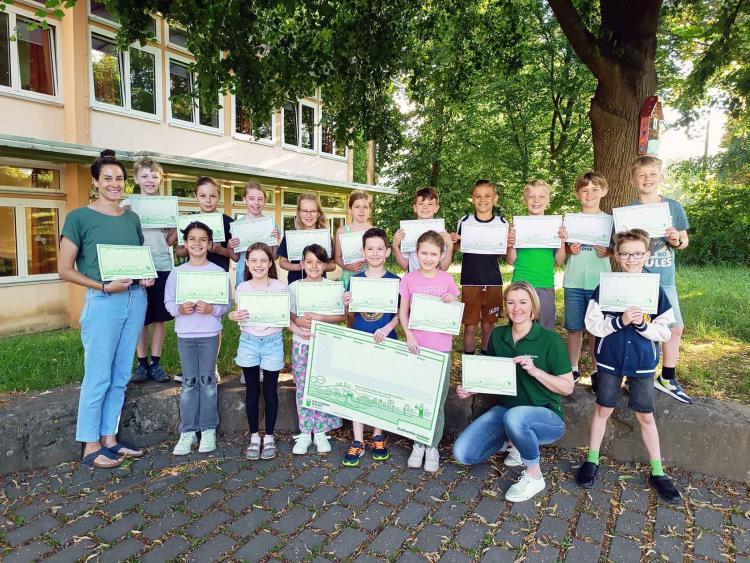 Die Schülerinnen und Schüler der Klasse 3c der Grundschule Hennen freuen sich sehr über die Überraschung.  v.l.n.r. Frau Schulze, Klassenlehrerin, Schülerinnen und Schüler der Klasse 3c der Grundschule Hennen, Frau Hohmann-Stock, Stadtwerke Iserlohn 